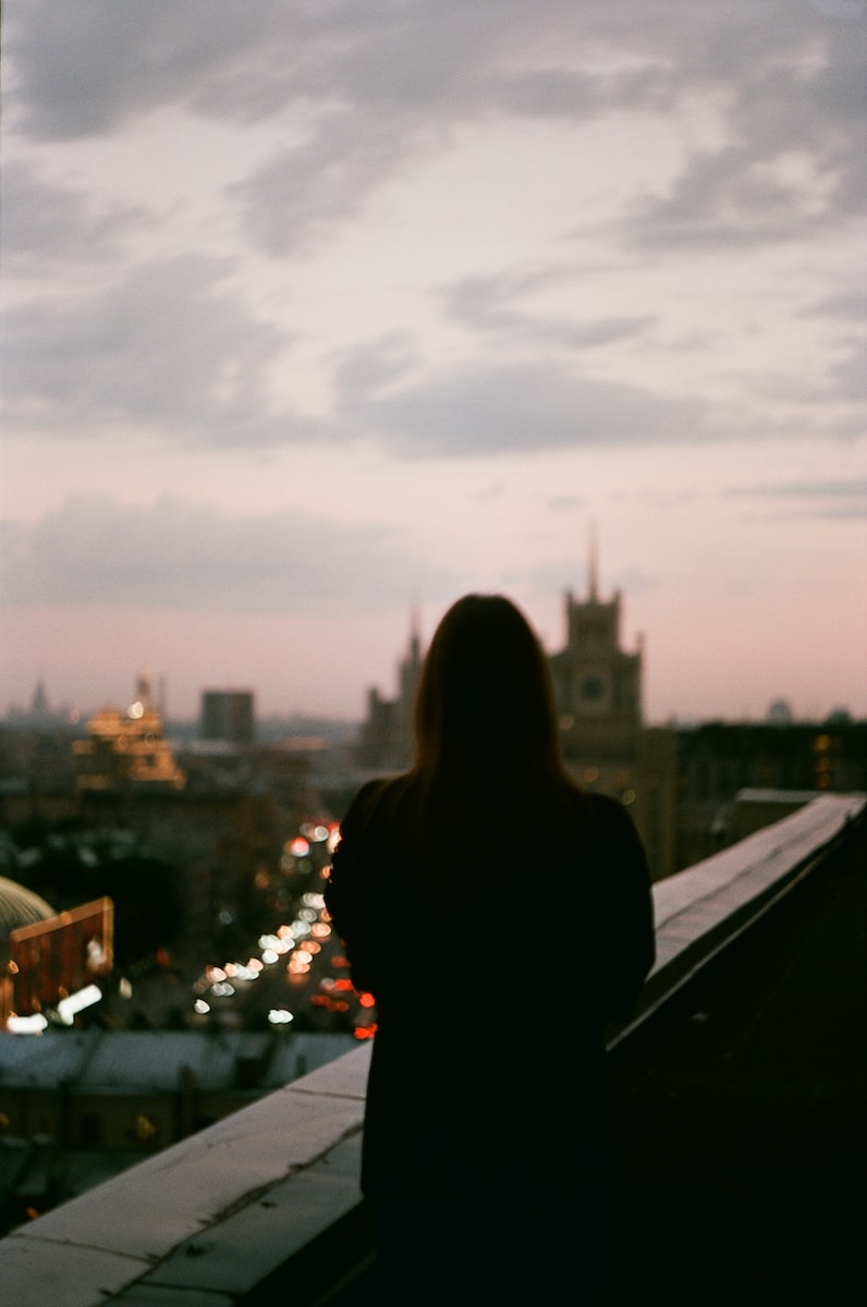 a woman standing on top of a roof next to a tall building